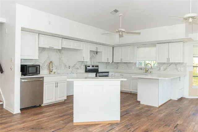 a kitchen with stainless steel appliances granite countertop a white cabinets and wooden floor
