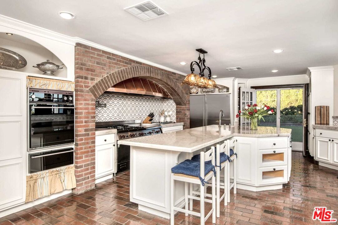 25045 Jim Bridger Road Hidden Hills, CA 91302 - Photo 24 of 52 a kitchen with a sink a stove and chairs