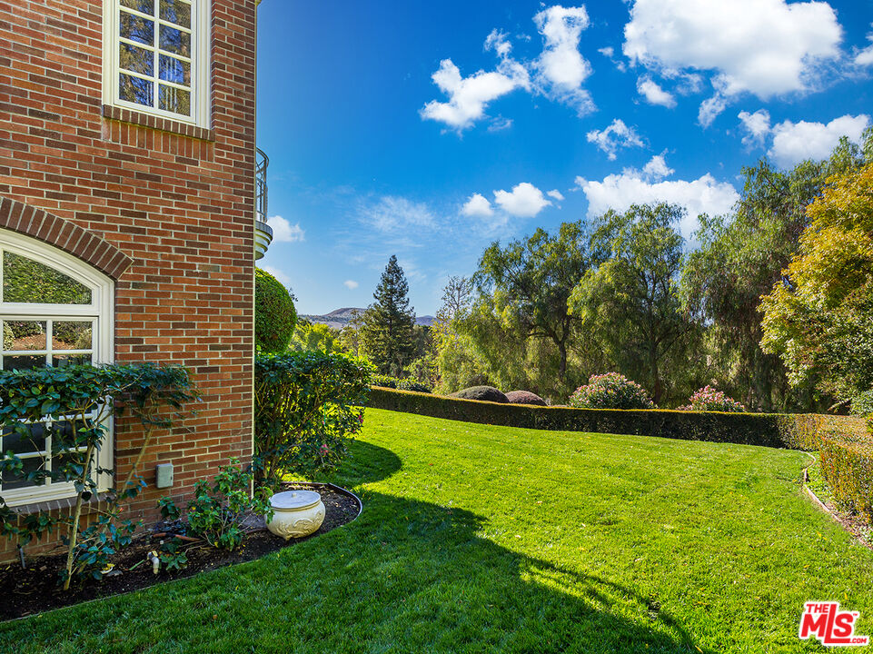 25045 Jim Bridger Road Hidden Hills, CA 91302 - Photo 52 of 52 a view of a garden with a building in the background