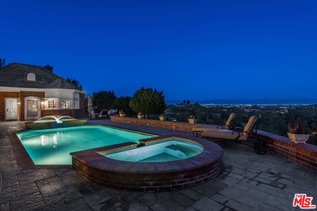 25045 Jim Bridger Road Hidden Hills, CA 91302 - Photo 10 of 52 a view of a swimming pool with lawn chairs under an umbrella