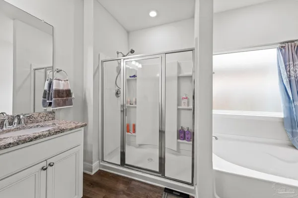 a bathroom with a granite countertop shower sink vanity and mirror