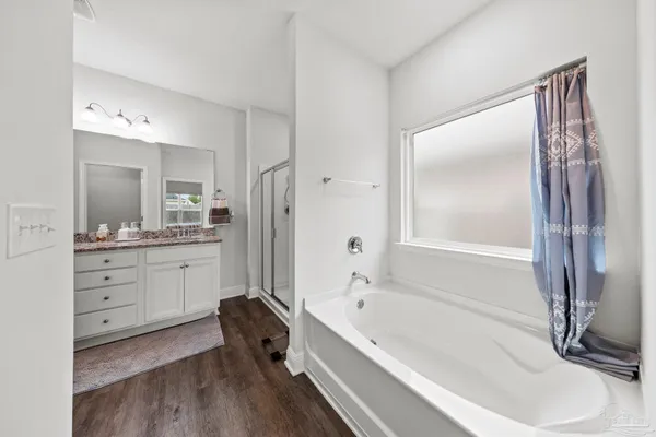 a bathroom with a tub sink double vanity and a mirror