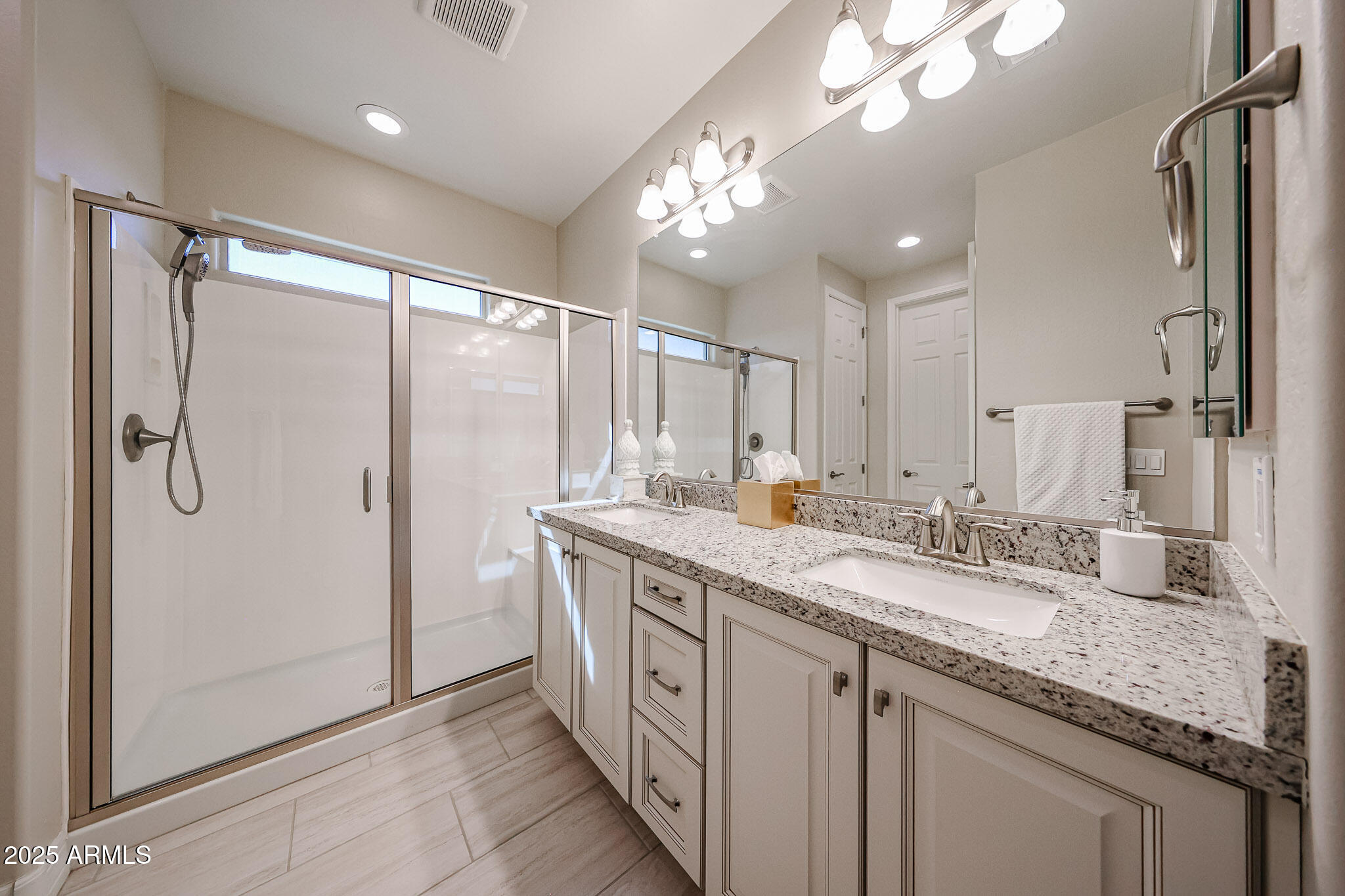 18184 West Deer Creek Road Goodyear, AZ 85338 - Photo 39 of 82 a spacious bathroom with a granite countertop sink a mirror and a shower