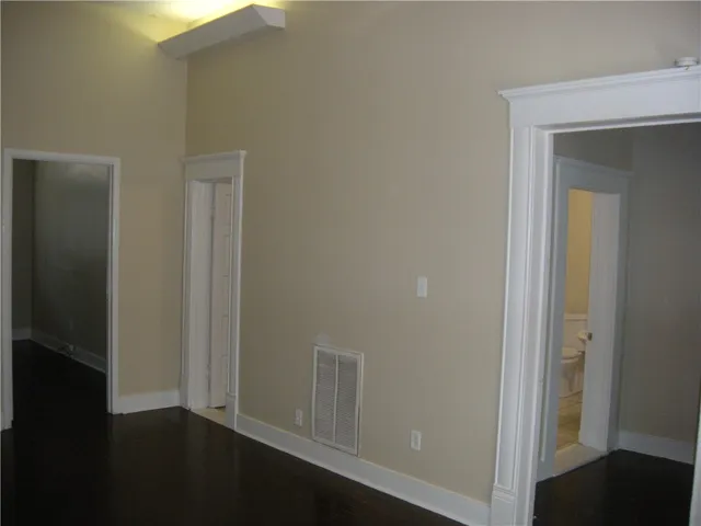 an empty room with wooden floor closet and windows