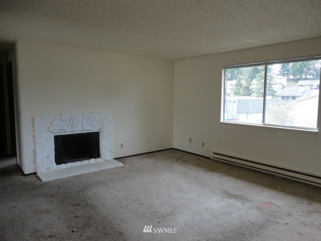 3901 Mason Loop Road Tacoma, WA 98409 - Photo 3 of 12 a view of an empty room with a fireplace and a window