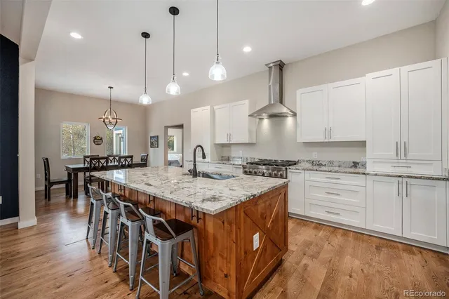 a kitchen with stainless steel appliances kitchen island granite countertop a stove a sink and white cabinets with wooden floor