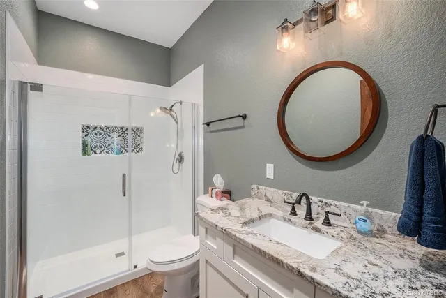 a bathroom with a granite countertop toilet a sink and a mirror