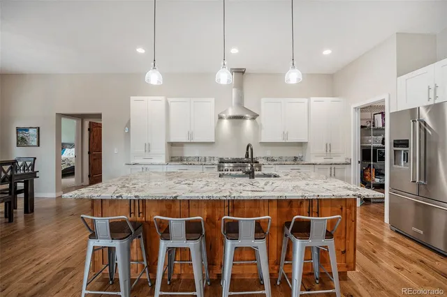 a kitchen with granite countertop kitchen island stainless steel appliances a sink and a refrigerator