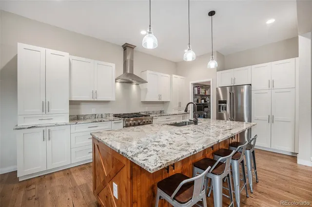 a kitchen with stainless steel appliances granite countertop a stove a refrigerator a kitchen island a sink and chairs
