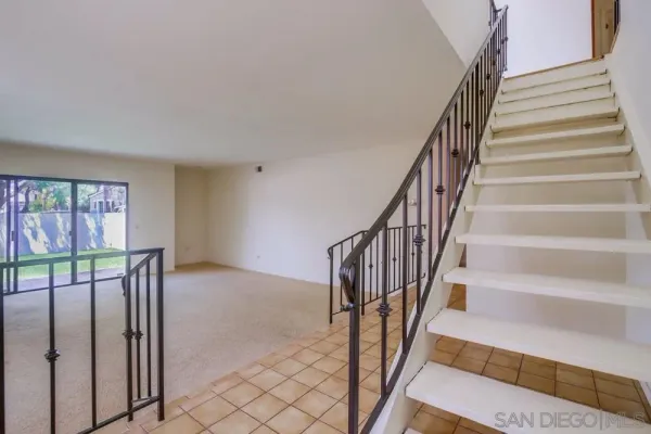 a view of empty room with wooden floor and kitchen view