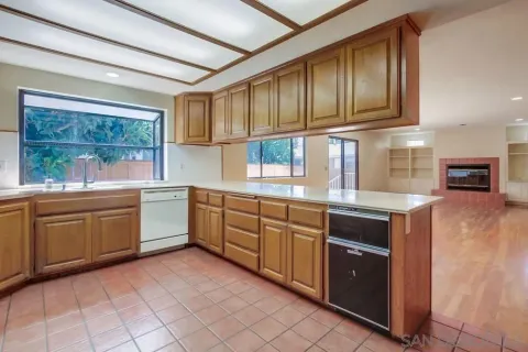 a view of an empty room with wooden floor and fan