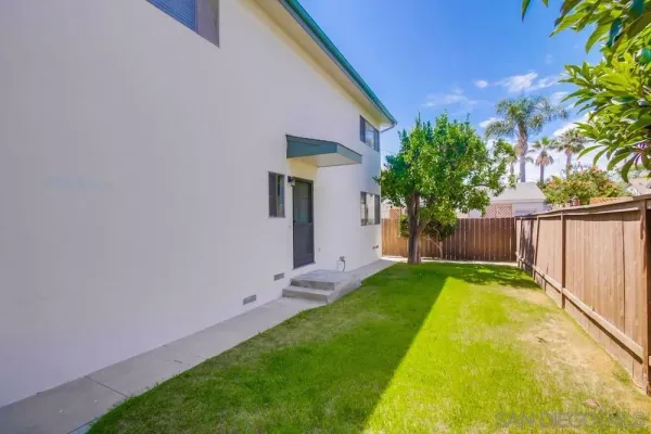 a view of a backyard with wooden fence and a bench