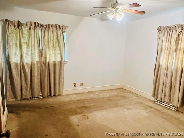 an empty room with a window and ceiling fan