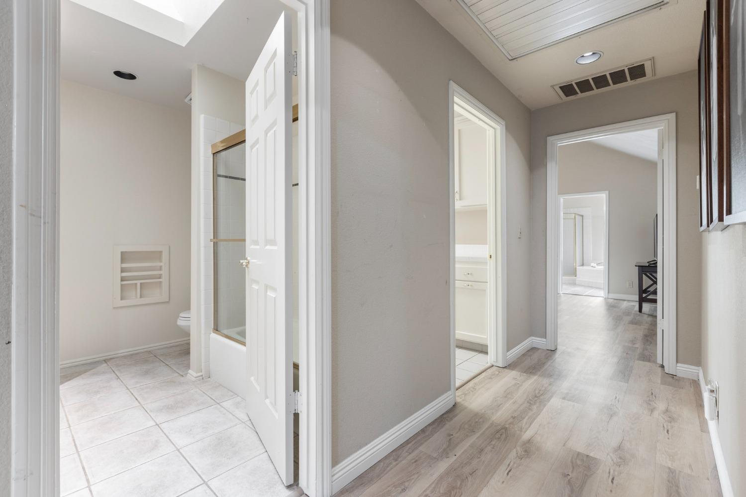 2128 Swift Avenue Clovis, CA 93611 - Photo 13 of 25 a view of a hallway with wooden floor and a bathroom