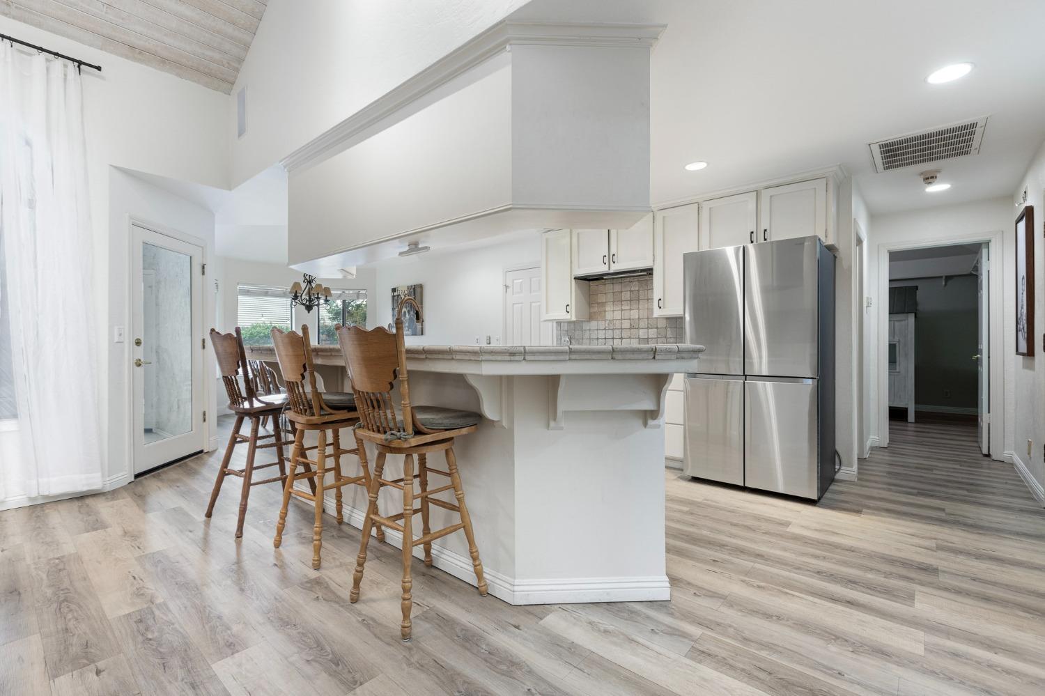 2128 Swift Avenue Clovis, CA 93611 - Photo 8 of 25 a kitchen with stainless steel appliances a dining table chairs refrigerator and cabinets