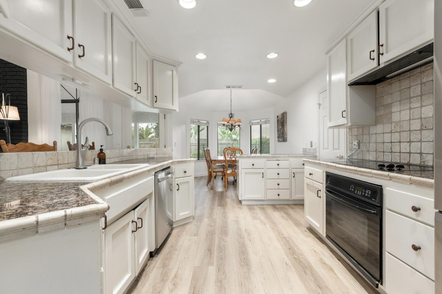 2128 Swift Avenue Clovis, CA 93611 - Photo 9 of 25 a large white kitchen with lots of counter space a sink dishwasher and a stove with wooden floor
