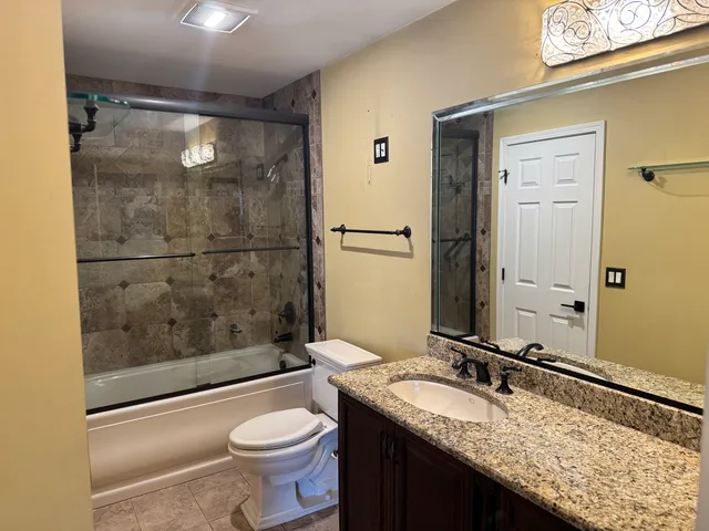 a bathroom with a granite countertop sink toilet and shower