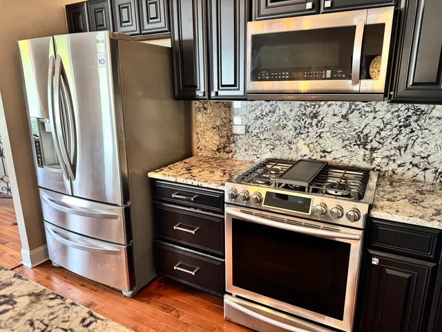 a kitchen with granite countertop white cabinets and stainless steel appliances
