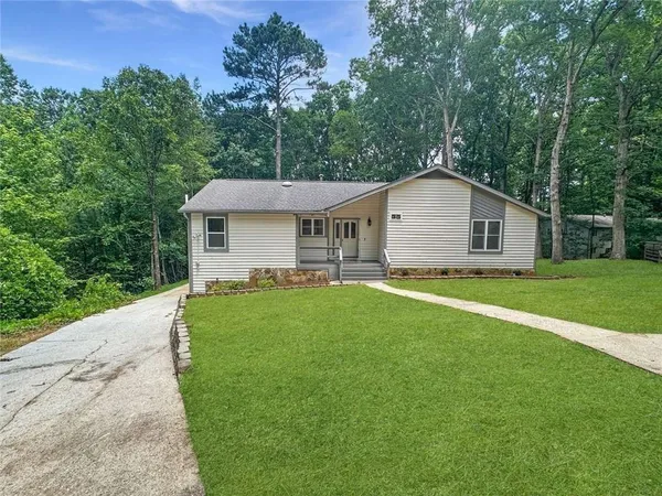 a view of a yard in front of a house with plants and large tree
