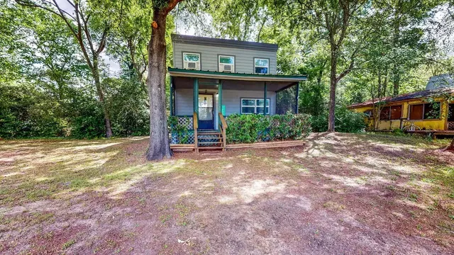 a view of a house with a yard and large tree