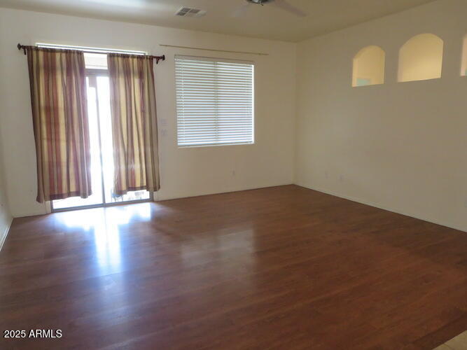 7120 South 68th Avenue Laveen, AZ 85339 - Photo 13 of 17 an empty room with wooden floor and windows with curtains