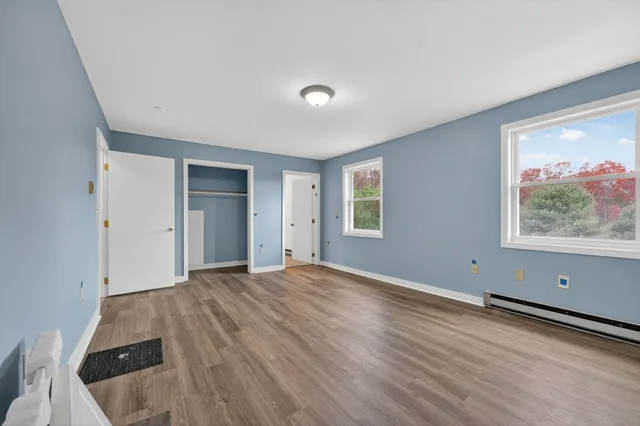 a view of an empty room with wooden floor and windows