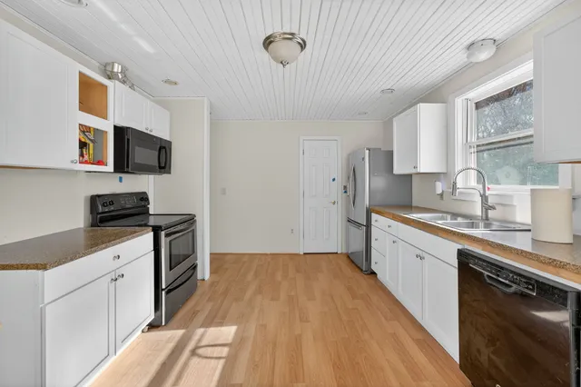 a kitchen with granite countertop a sink cabinets stainless steel appliances and a counter top space