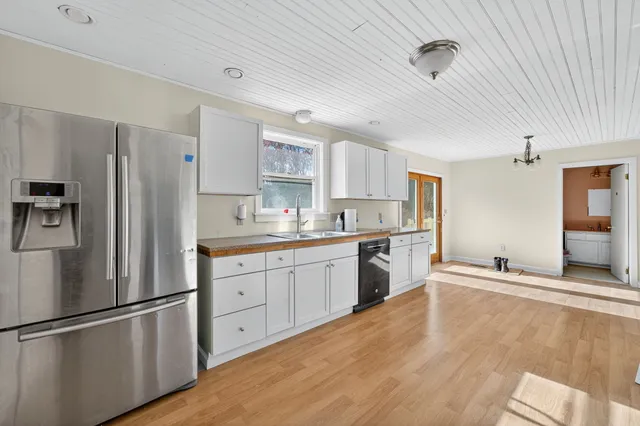 a kitchen with stainless steel appliances granite countertop a refrigerator a sink dishwasher a stove and white countertops with wooden floor