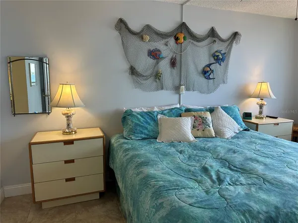 a bedroom with a bed and a lamp on dresser