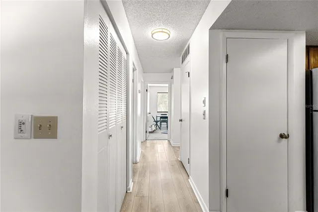 a view of a hallway with wooden floor and a bathroom