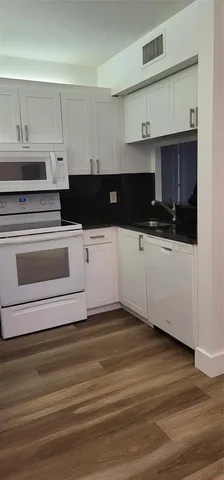 a kitchen with granite countertop a stove and white cabinets