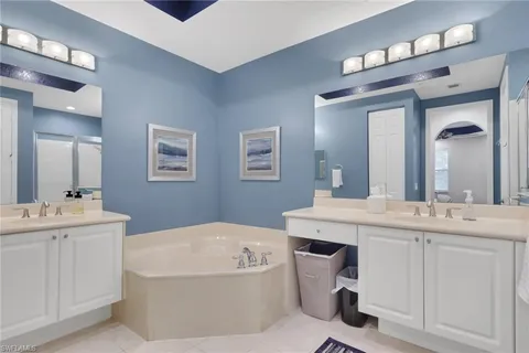 a bathroom with a tub a double vanity sink and a mirror