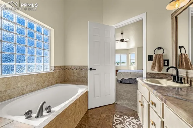 a bathroom with a granite countertop tub a sink and a window