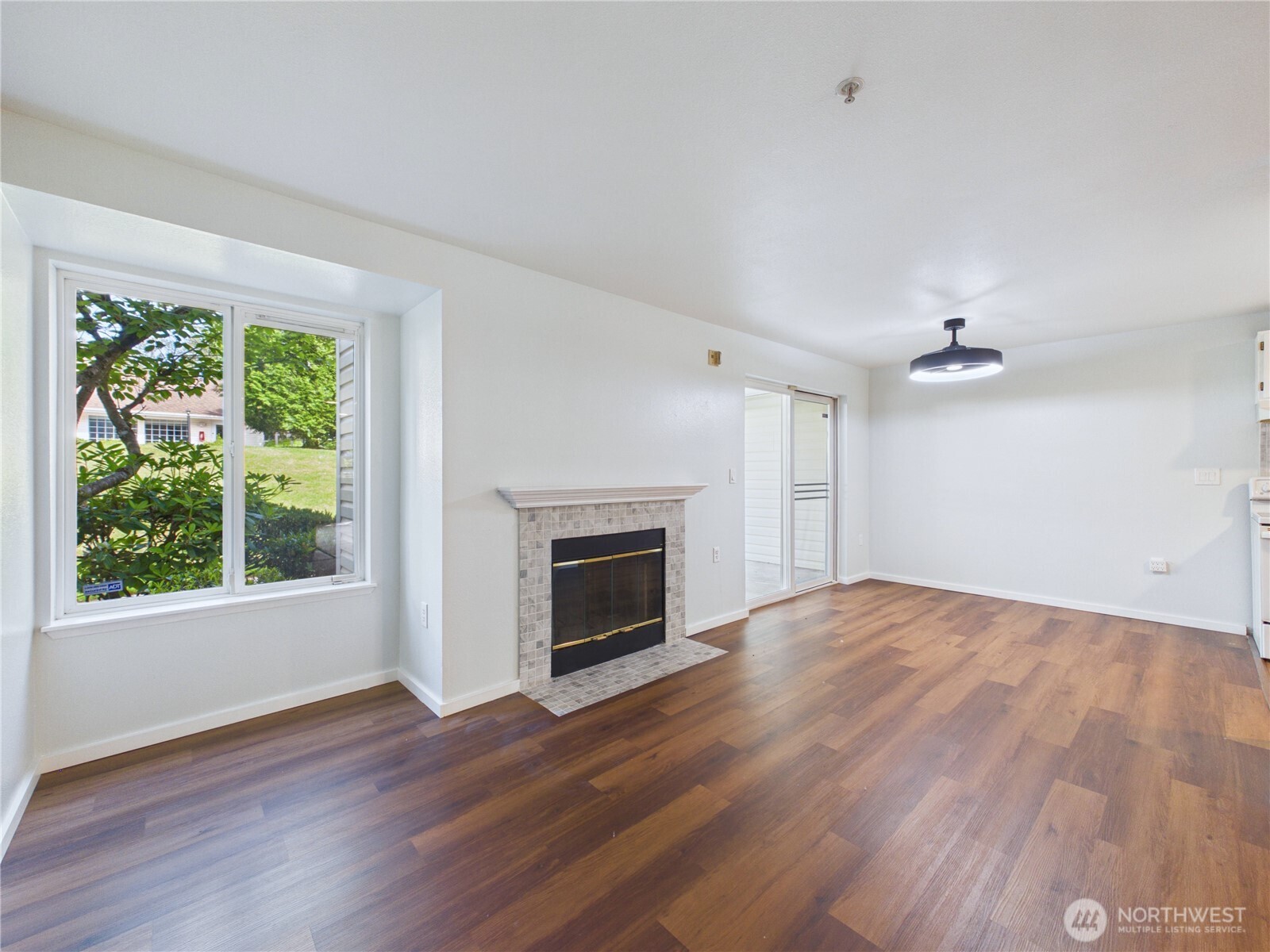 11002 Southeast Petrovitsky Road, Unit I102 Renton, WA 98055 - Photo 4 of 24 an empty room with wooden floor fireplace and windows