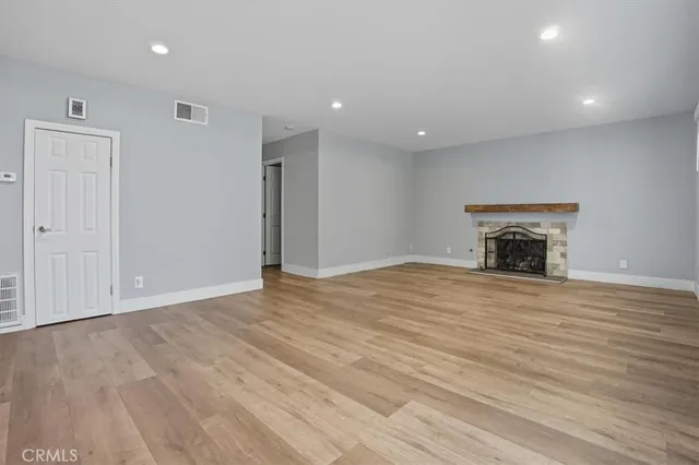 a view of empty room with wooden floor and fireplace