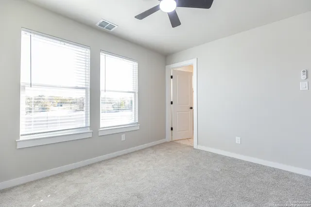 an empty room with a window and a ceiling fan