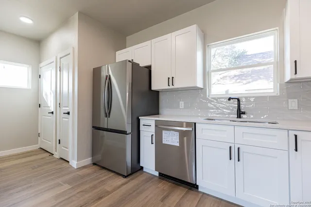 a kitchen with granite countertop a stove top oven a sink and dishwasher a microwave oven with white cabinets