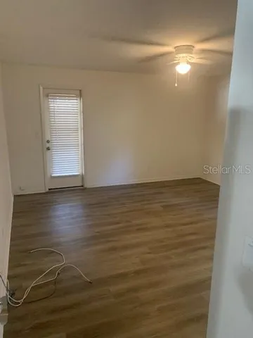 a view of an empty room with wooden floor and a window