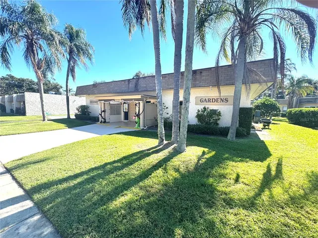 a view of swimming pool with a garden and palm trees