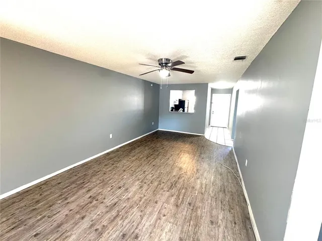 an empty room with wooden floor and fan