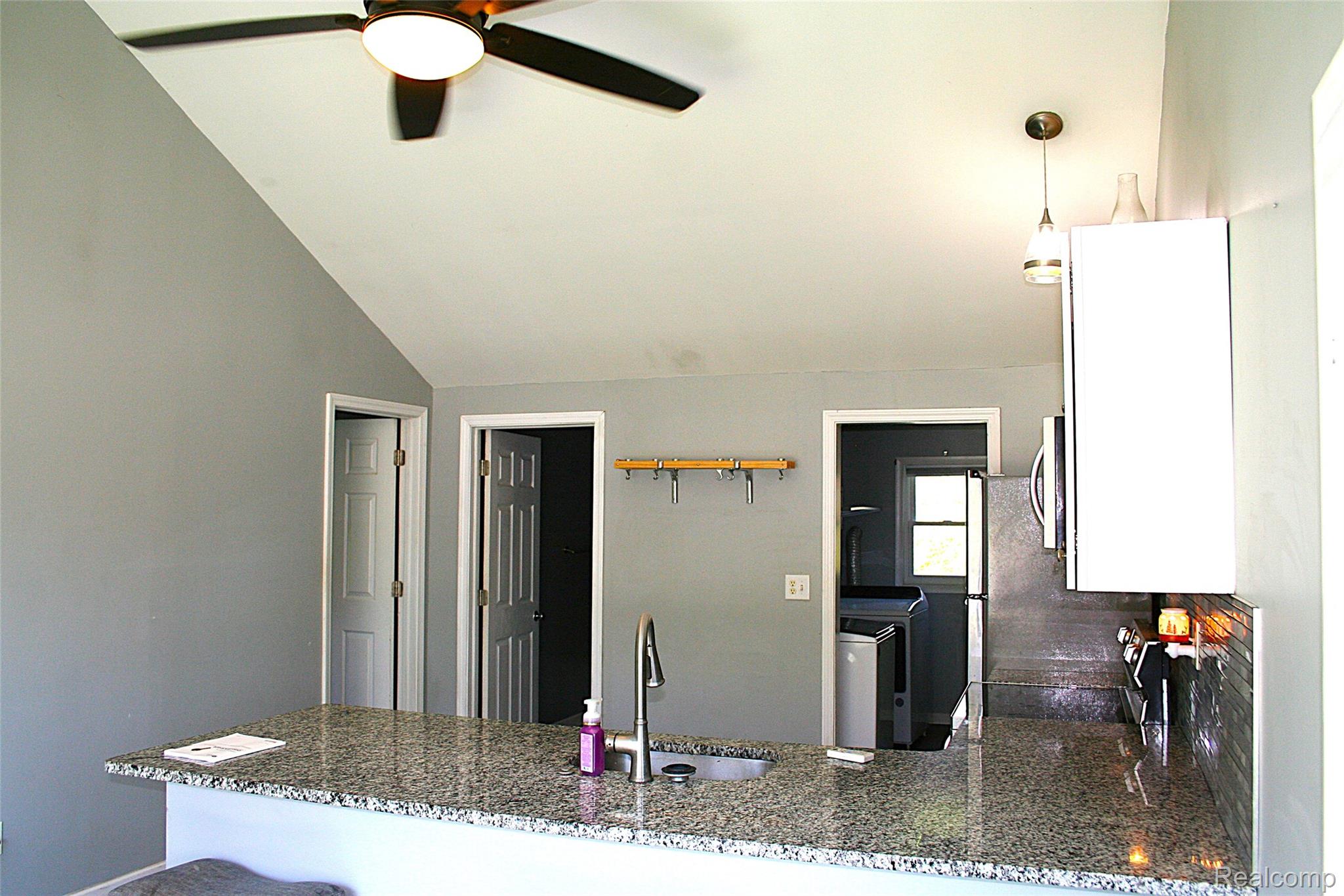 2199 Sandy Creek Road Monroe, MI 48162 - Photo 8 of 13 Kitchen with dark stone countertops, a peninsula, white cabinetry, a ceiling fan, and vaulted ceiling