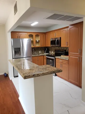 a kitchen with stainless steel appliances granite countertop a refrigerator a stove a sink and a oven