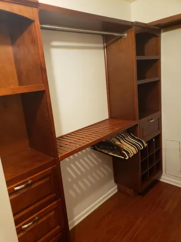 an empty room with wooden floor staircase and a kitchen view