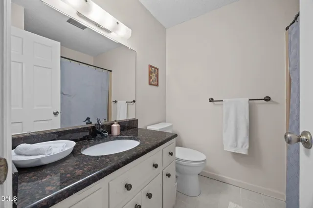 a bathroom with a granite countertop sink a toilet a mirror and shower