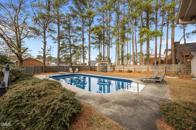 a view of swimming pool with lawn chairs and trees