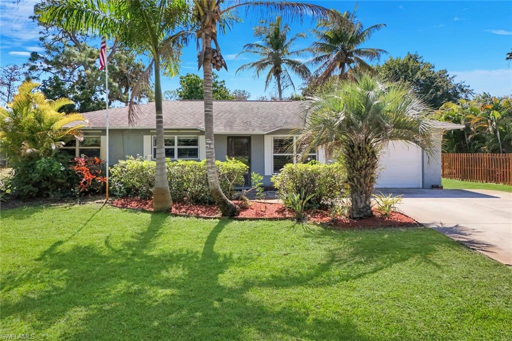 a view of a house with a yard and palm trees