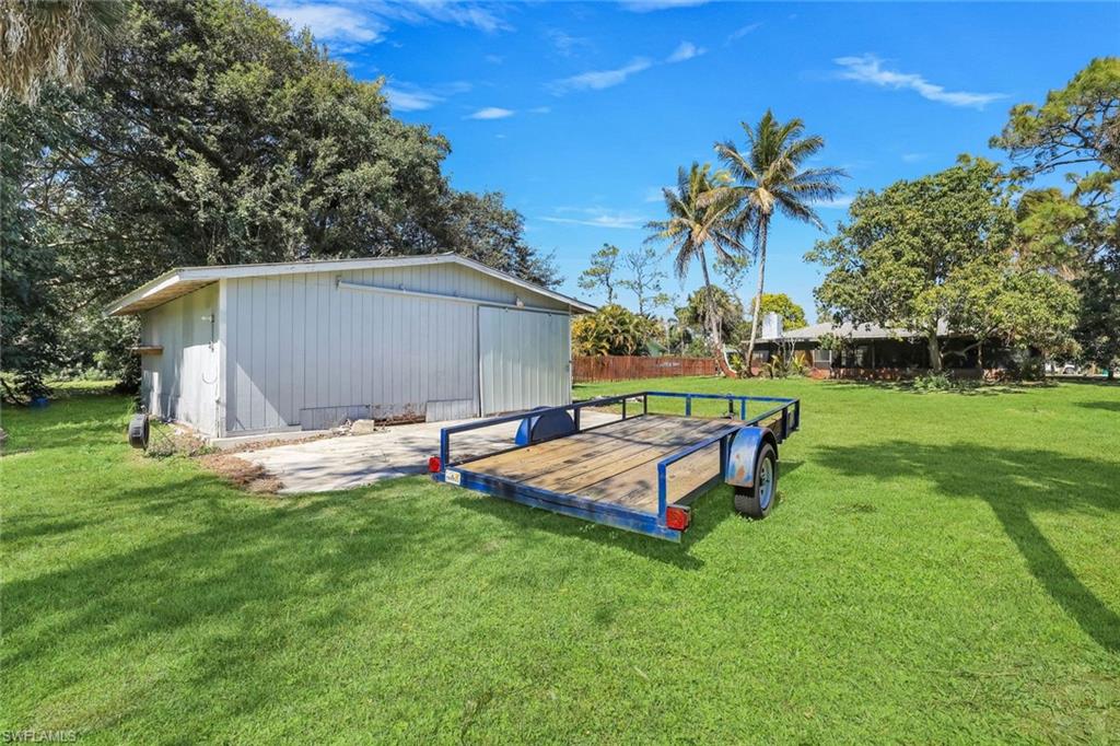 5290 Cypress Lane Naples, FL 34113 - Photo 26 of 35 a view of a backyard with table and chairs and potted plants and large tree
