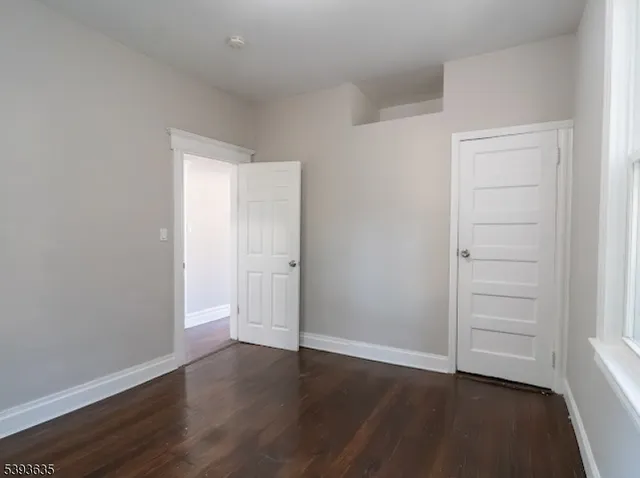 an empty room with wooden floor & closet area