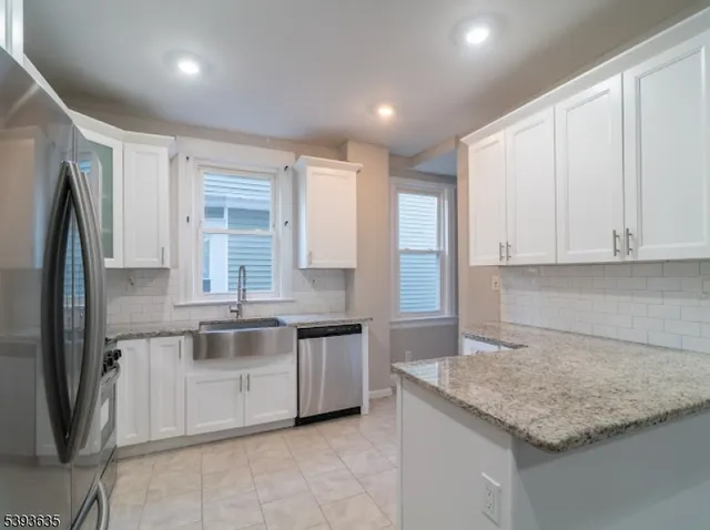 a kitchen with stainless steel appliances granite countertop a sink and a refrigerator
