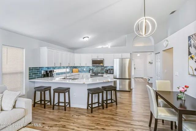 a kitchen with stainless steel appliances granite countertop a dining table chairs stove and white kitchen view
